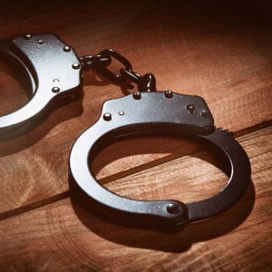 violent-felonies-square Local Criminal Defense Lawyer, silver handcuffs on wooden table, parole violation