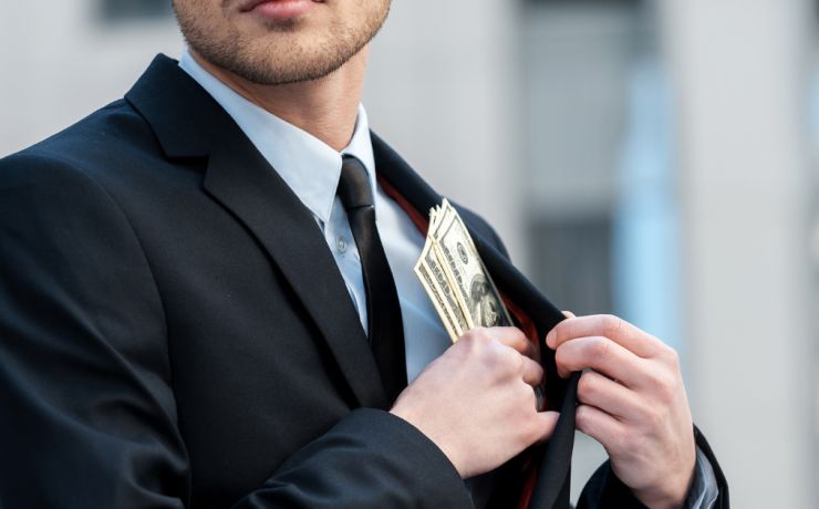 Embezzlement Defense - What to Do When You are Charged with Embezzlement - man tucking cash into his suit jacket pocket
