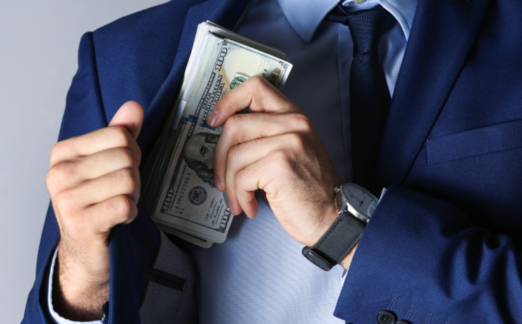 What You Need to Know if You've Been Charged with Embezzlement - man putting money in suit pocket