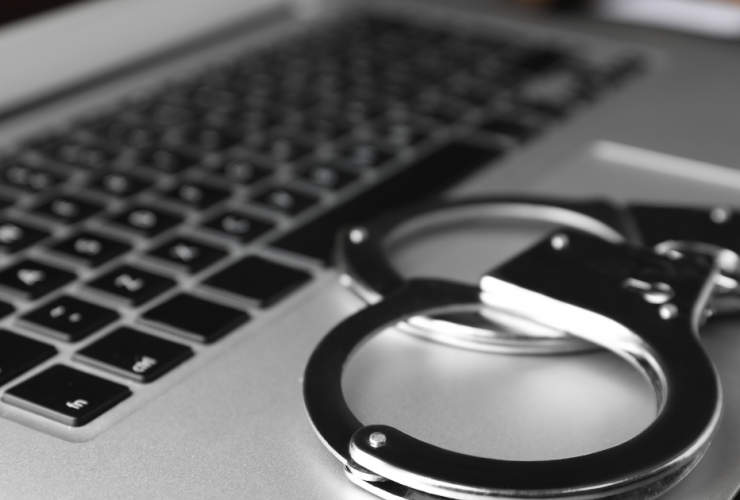 I've Been Charged with Cyber Crime, What Do I Do Next? - closeup of handcuffs on laptop