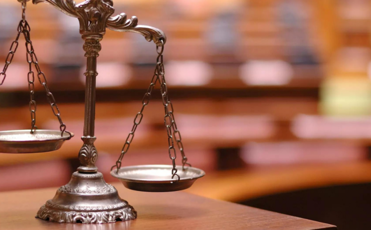 What Does Above the Law Mean? - unbalanced scale on wood tabletop with shelves of books blurred in the background