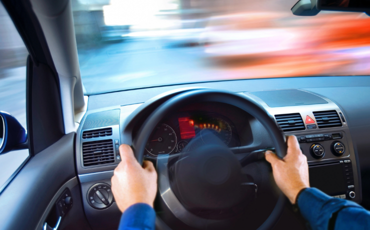 What is the Legal Limit for Driving High? view from the drivers seat of a car, hands on the steering wheel, with objects outside of the car blurred
