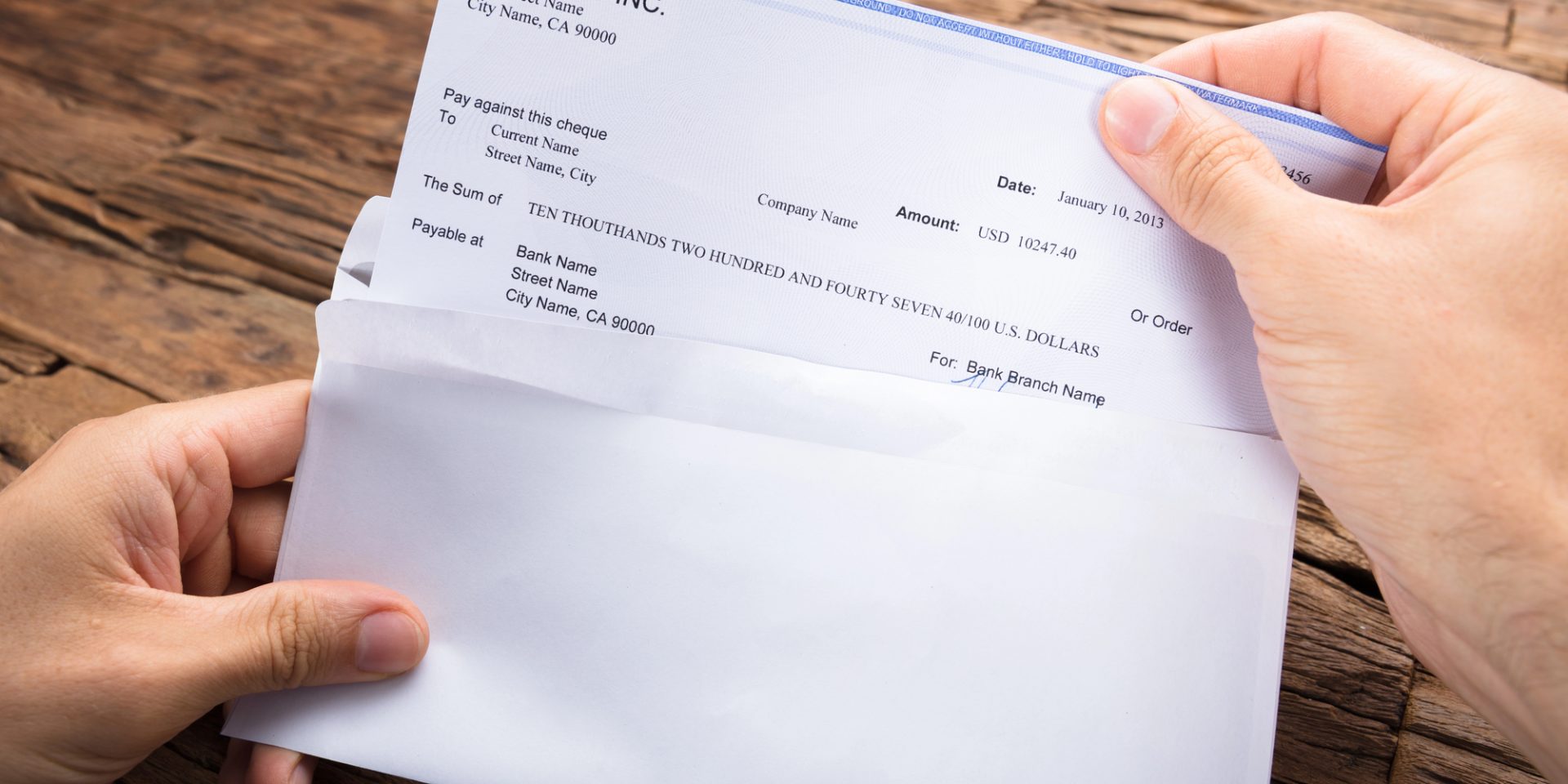 How Serious Are Wage Theft Charges? Someone opens their paycheck from an envelope at their table.
