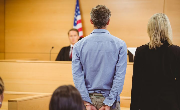 What Happens After a Felony Arrest in California? A lawyer and defendant stand before a judge in a courtroom.