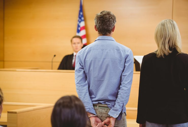 What Happens After a Felony Arrest in California? A lawyer and defendant stand before a judge in a courtroom.